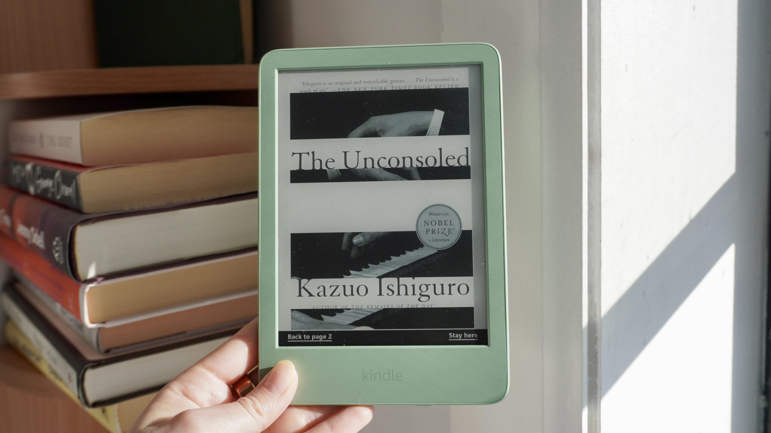 amazon kindle in one hand with all book background